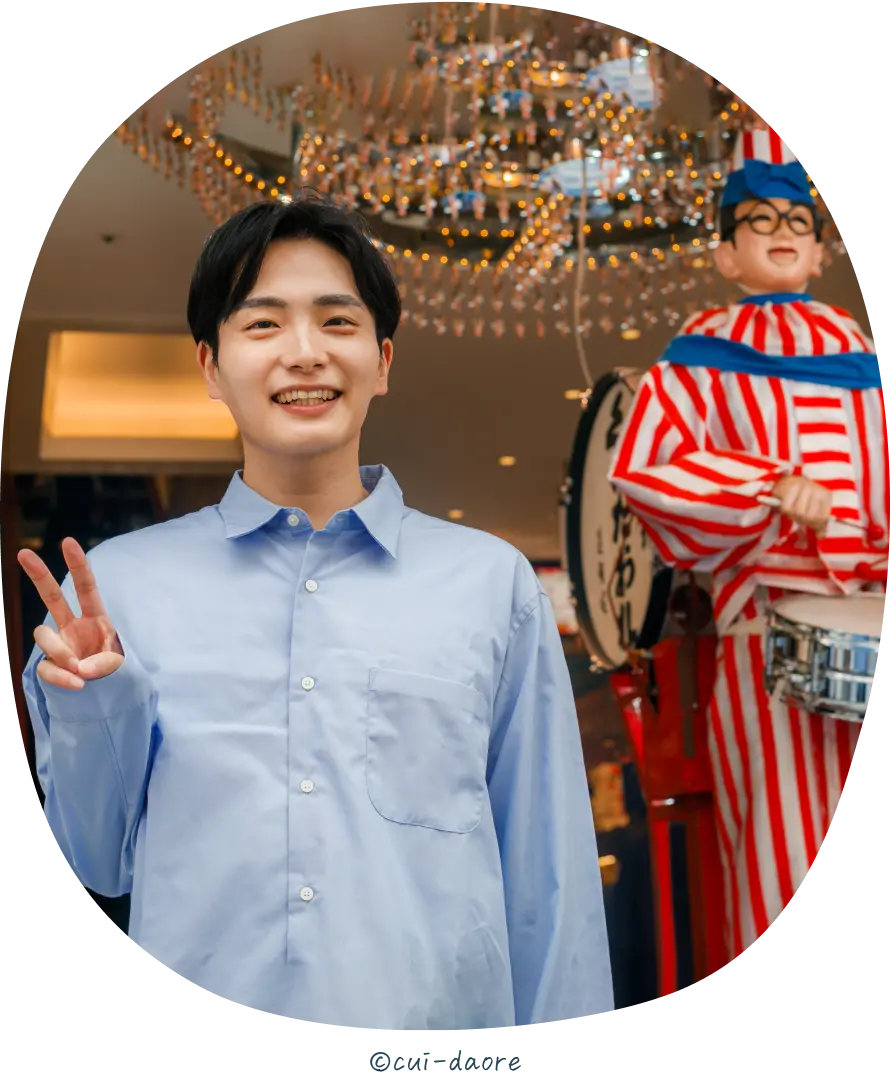 食い倒れ人形の前に立っている男性の写真